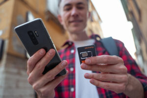 Man in red plaid shirt with a gadget and SIM card in hands
